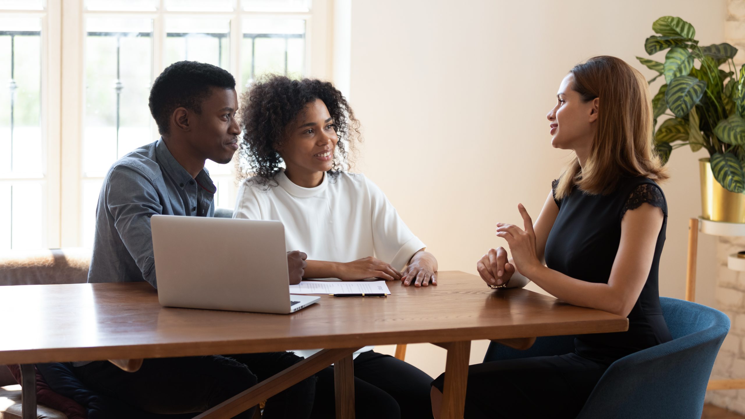 Young couple sitting at table discussing funeral and payment options with a female funeral director.