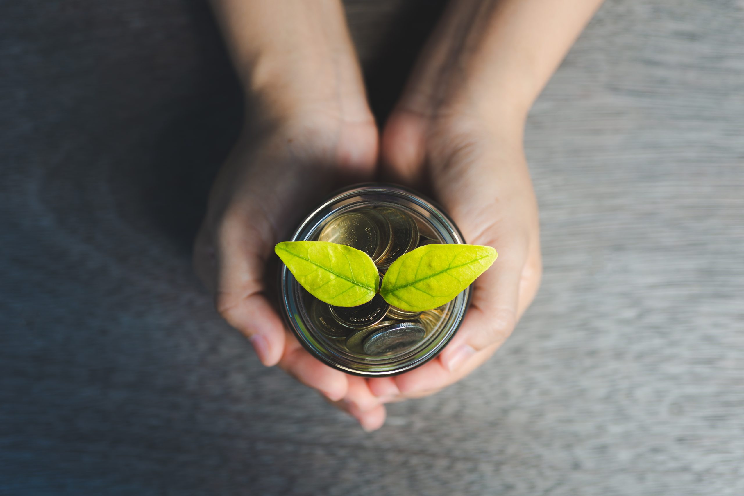 Woman holding a jar of coins with a plant growing out of it - Simplifying life insurance assignments with Family Funeral Funding