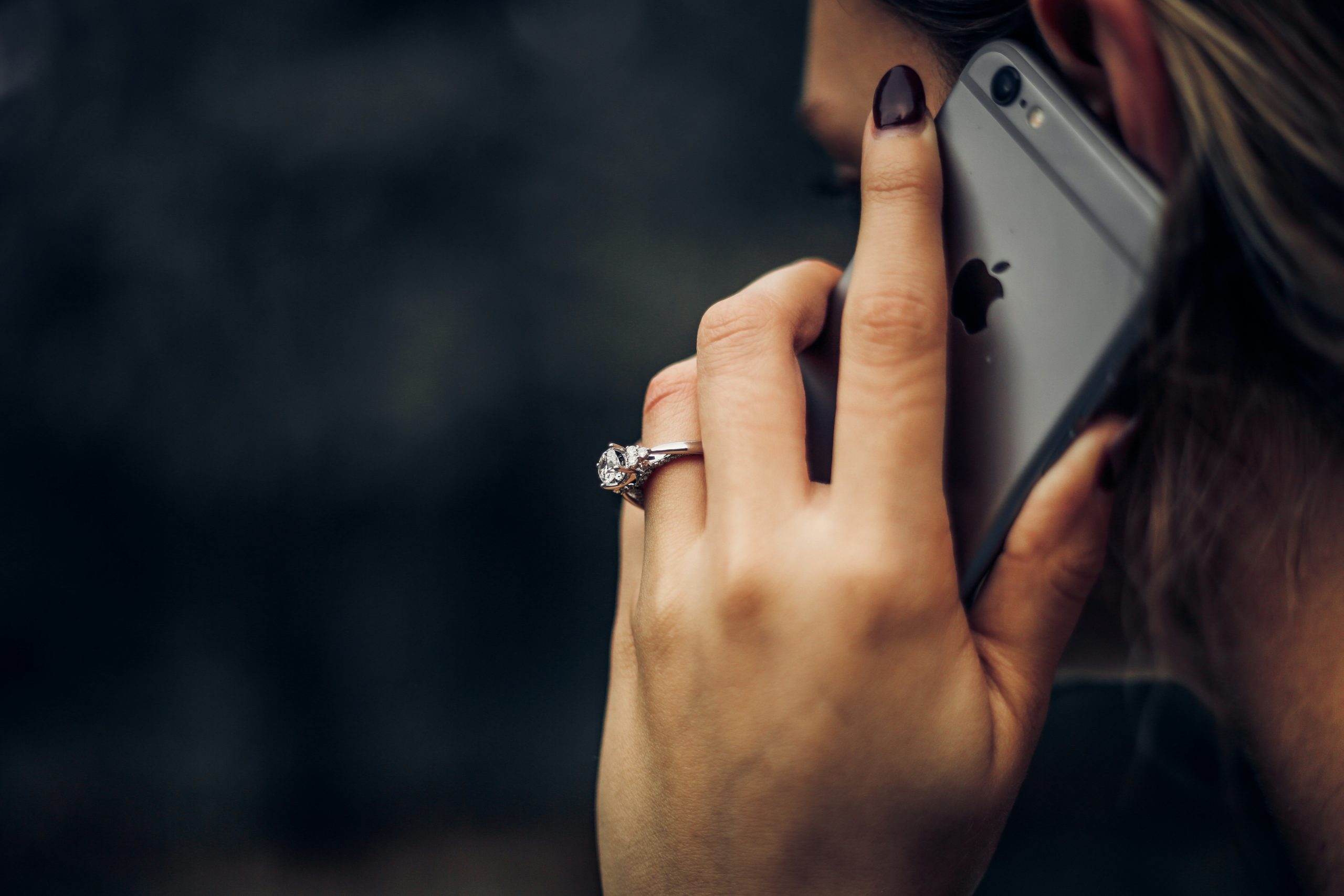 Woman on iPhone, a candid shot of side of face and hand with wedding ring | Can Funeral Homes Search for Life Insurance Policies? | Family Funeral Funding - Helping Families with After Death Expenses | Bridging the gap between families, funeral homes and life insurance companies.